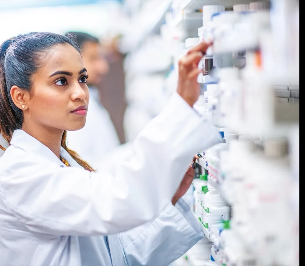 Pharmacist checking medicines on dispensary shelves