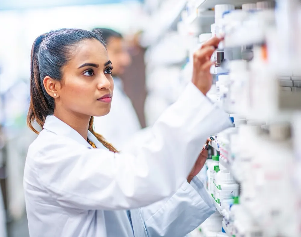 Pharmacist checking medicines on dispensary shelves
